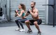 Kneeling muscular couple exercising with kettlebells
